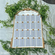 the seating chart for an outdoor wedding is displayed on a white tablecloth with greenery