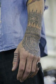 a man with a tattoo on his arm and hand holding something in the other hand