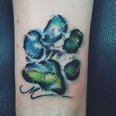 a paw print tattoo on the left arm and leg, with green dots around it