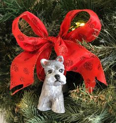 a dog ornament hanging from a christmas tree with a red bow on it