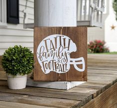 a wooden sign that says faith, family and football next to a potted plant