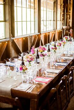 a long table is set with wine glasses and flowers in vases on the tables