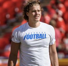 a man in a white shirt is standing on the field with his hands behind his back