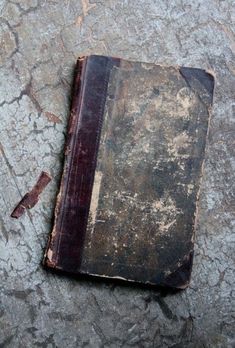 an old book laying on the ground with peeling paint and chipping off it's cover