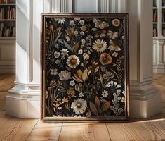 a painting on the floor in front of a bookcase with bookshelves and flowers