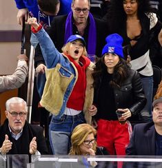 two women standing next to each other in front of a crowd at a sporting event