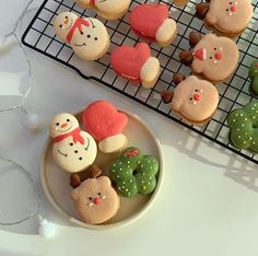 several decorated cookies are on a plate next to a cooling rack with christmas themed cookies