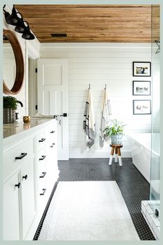 a bathroom with black and white tile flooring and wooden ceiling above the bathtub