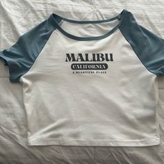 Malibu Baby Tee. Never Worn Blue Tops With Text Print For Spring, Basic Blue Tops With Text Print, Blue Text Print Tops For Spring, Cute Blue Tops With Graphic Print, Trendy Blue Top With Text Print, Trendy Blue Tops With Text Print, Casual Blue Tops With Text Print, Trendy Light Blue Top With Letter Print, Light Blue Basic Tops With Graphic Print