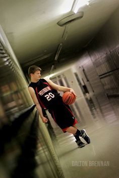 a young man holding a basketball while standing in a hallway