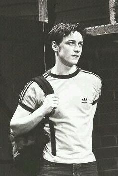 a young man standing in front of a brick wall