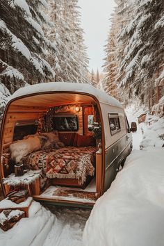 an old camper van is parked in the snow with its bed pulled up to it's side