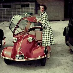 a woman standing next to an old fashioned car