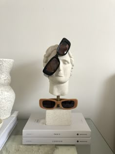 a white head with sunglasses sitting on top of a stack of books