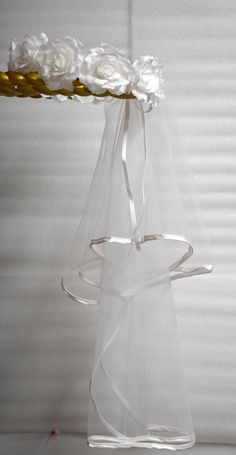 a clear vase with white flowers in it and a ribbon tied around the top, on a table