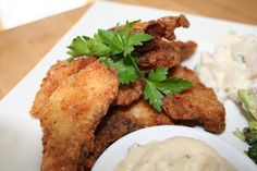 fried chicken and broccoli on a white plate with ranch dressing next to it