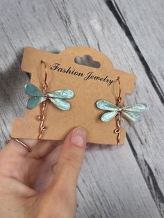 the dragonfly earrings are on display in front of a cardboard card that says fashion jewelry