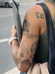 a person with tattoos on their arm is holding a book and looking down the street