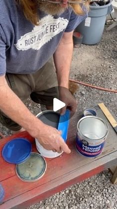 a man is painting some blue paint on a table with red and white buckets