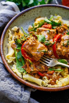 a bowl filled with pasta and meat covered in sauce