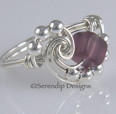 a silver ring with a purple stone in the center