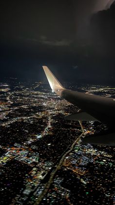 an airplane wing flying over a city at night