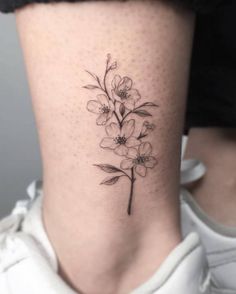 a woman's lower leg with a flower tattoo on the bottom of her thigh