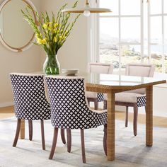 a dining room table with four chairs and a vase filled with flowers on top of it