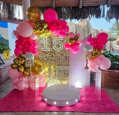 the table is set up with pink and gold balloons, white pedestals, and a large number 15 sign