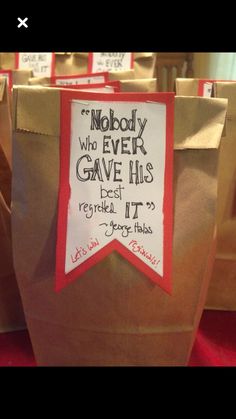 some brown paper bags with red and white ribbons on them that say nobody who ever gave his