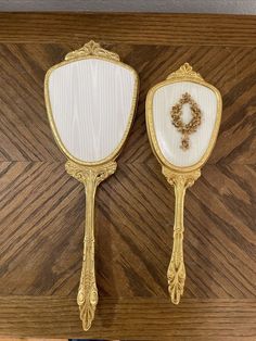 two ornate gold and white mirrors on a wooden wall