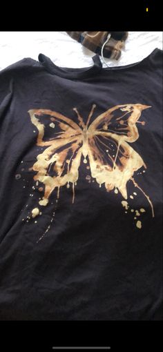 a black shirt with a yellow butterfly on it's chest and the bottom half of its wings