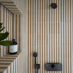 a bathroom with striped wallpaper and black faucet next to the shower head