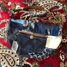 a purse is sitting on top of a red and blue floral print fabric with gold hardware