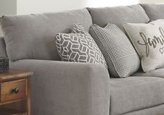 a gray couch with pillows on it and a wooden table in front of the couch