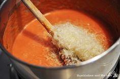 a wooden spoon in a pot filled with soup and grated parmesan cheese