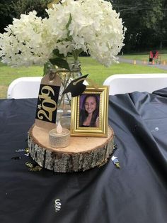 a vase filled with white flowers sitting on top of a wooden table next to a tree stump