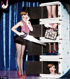 a woman is holding a giant pair of scissors in front of a shelf with photos on it