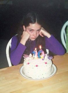 a woman sitting at a table in front of a birthday cake with candles on it