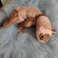 a stuffed animal laying on top of a fluffy blue blanket with its eyes closed and nose open