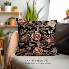 a black pillow with pomegranates and leaves on it sitting on a chair