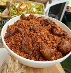 a bowl filled with rice and meat on top of a wooden table next to other food items