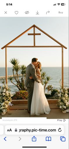 a bride and groom kissing in front of a gazebo with the ocean in the background