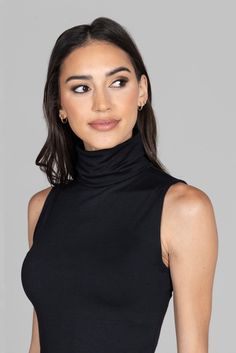 Why we love this: This black sleeveless turtleneck is a year-round essential! Made from super soft, luxe fabric, this classy & elegant top can be dressed up or down! Pair it with any of our black pants for a classic black-on-black outfit. Features: KiraGrace Luxe: Feels ultra-soft and luxurious Close-fitting, ultra soft, and smooth Effortlessly transitions from desk-to-dinner Elegant mock neck silhouette Made in U.S.A. of imported fabric FIT: Fitted, hip-length tank that stays put COVERAGE: High Check Mark, Travel Pants, Sleeveless Turtleneck, Yoga Tops, Black Sleeveless, High Neckline, Tight Leggings, Tops For Leggings, Black Outfit