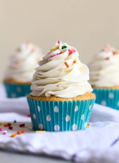 three cupcakes with white frosting and sprinkles