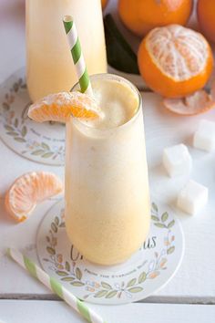 two glasses filled with orange juice on top of a white plate next to sliced oranges