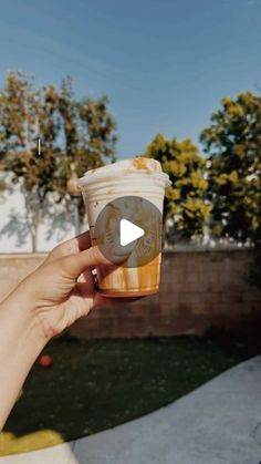 a person holding up a cup of coffee in their hand with the video below it