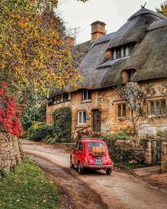 a red van parked in front of a stone house with thatched roof and windows