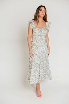 Whether you're frolicking through a field of wildflowers, touring a sunny Greek isle, or attending a springtime baby shower, the Emery Midi Dress will ensure you do it looking like a goddess. We designed this premium dress with an ultra-flattering neckline and a figure-skimming silhouette, paired with a flounced skirt and sweet ruffle details. The Emery is guaranteed to be one of your most feminine (and most favorite!) pieces. FIT: Runs very fitted. This dress is designed with a fit-and-flare pr Blue Ditsy Floral Print Midi Dress For Spring, Spring Blue Midi Dress With Ditsy Floral Print, Blue Midi Dress With Ditsy Floral Print For Spring, Spring Printed Dress For Garden Party, Spring Garden Party Dress With Print, Spring Garden Party Printed Dress, Spring Vacation Sundress With Flutter Sleeves, Short Sleeve Floral Print Picnic Dress, Spring Sundress With Flutter Sleeves