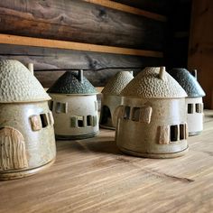 three ceramic houses sitting on top of a wooden table